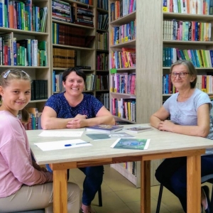 Pani Beata, pani Grażynka i Lenka w bibliotece szukają informacji o Księdzu Edmundzie Roszczynialskim.